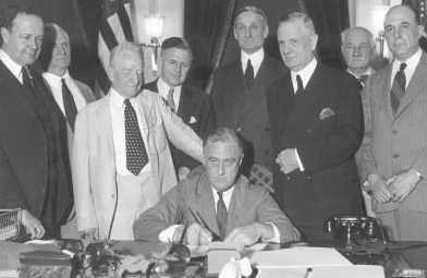 Photo showing President Franklin Roosevelt signing the Banking Act of 1933, a part of which established the FDIC; shown standing by his side are Senator Carter Glass of Virginia and Representative Henry Steagall of Alabama, 2 of the most prominent figures in the billâ€™s development.